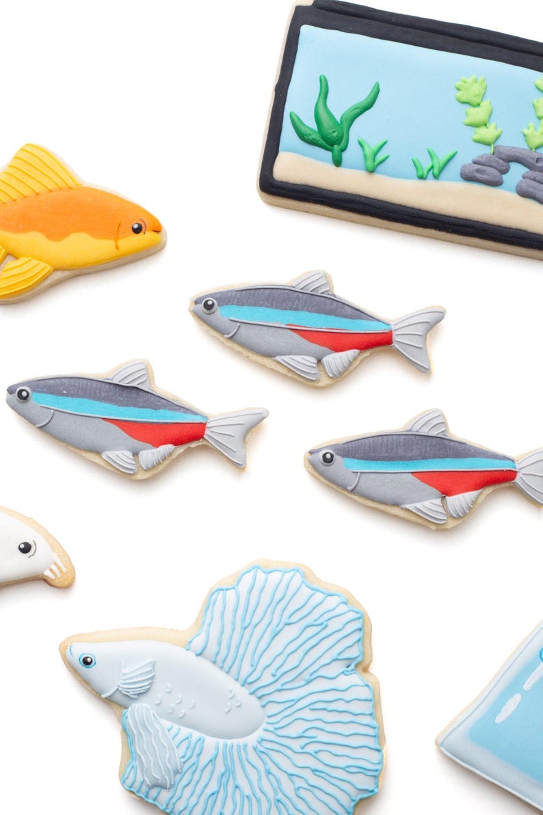 May include: Assortment of fish-shaped cookies, including a goldfish, several neon tetras, and a betta fish, all decorated with colorful icing. There is also a cookie shaped like an aquarium.
