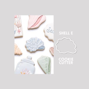 Puede incluir: Una colección de galletas decoradas con formas de diversas conchas marinas y un frasco, junto al contorno blanco de un SHELL E COOKIE CUTTER. Las galletas presentan colores pastel que incluyen azul claro, rosa suave y verde pálido con detalles.