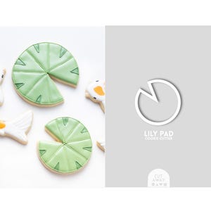 Könnte beinhalten: Ein Ausstecher in Form eines Seerosenblattes. Der Ausstecher ist weiß und hat einen Ausschnitt in Form einer Mondsichel. Der Text "Lily Pad Cookie Cutter" ist unter dem Ausstecher gedruckt.
