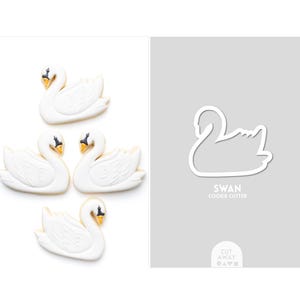 May include: Four white swan-shaped cookies with black and yellow details. Next to the cookies is a gray background with a white outline of a swan and the text "SWAN COOKIE CUTTER".
