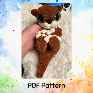 May include: A crocheted otter amigurumi toy with brown and white fur, large blue eyes, and a long tail. PDF Pattern.
