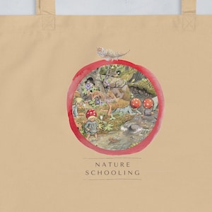 May include: A beige tote bag with a red circle design featuring a nature scene with a small animal and mushrooms. The text "NATURE SCHOOLING" is printed below the circle.