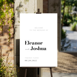Pu&ograve; includere: Cartello di benvenuto per matrimonio bianco con testo nero. Il cartello recita "Benvenuti al matrimonio di Eleanor e Joshua, Pinecrest, Florida, 08.20.2022".