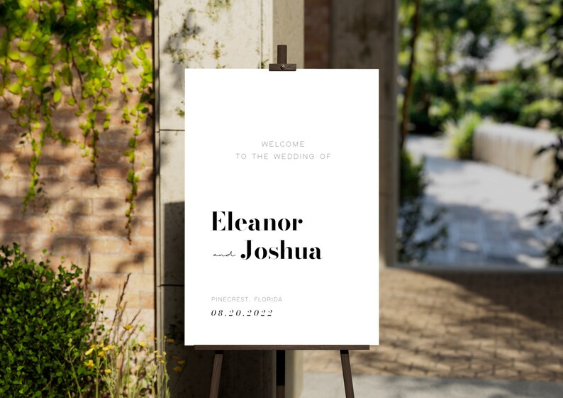 Pu&ograve; includere: Cartello di benvenuto per matrimonio bianco con testo nero. Il cartello recita "Benvenuti al matrimonio di Eleanor e Joshua, Pinecrest, Florida, 08.20.2022".