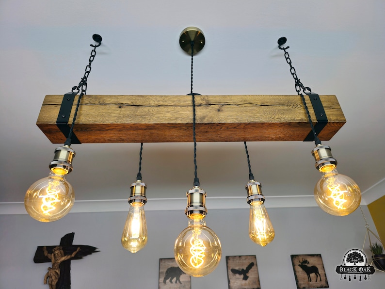 May include: A rustic wooden beam chandelier with five Edison bulb lights. The beam is stained a dark brown and has black metal brackets on each end. The bulbs are hanging from black cords and chains.
