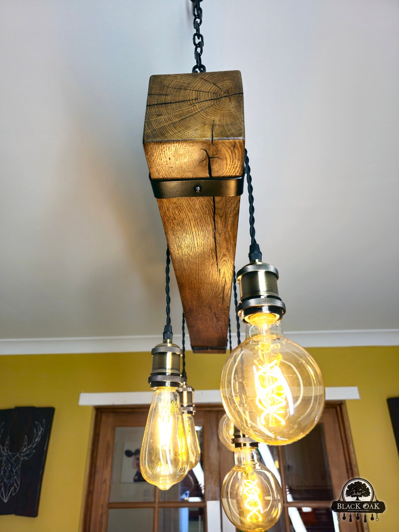 May include: A rustic wooden chandelier with six Edison bulb lights. The chandelier is made from reclaimed wood and has a black metal frame. The bulbs are hanging from black cords and have a warm, golden glow.