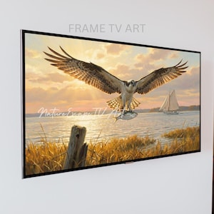 May include: A framed TV art piece featuring a painting of an osprey with outstretched wings carrying a fish. The artwork depicts a sunset over a body of water with a sailboat in the distance. The text "FRAME TV ART" and "Nature Escape TV Art" are visible.