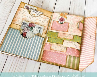 May include: A multi-layered scrapbook with a floral theme. The scrapbook has pockets and flaps for storing photos and mementos. The cover is decorated with a variety of patterned papers and embellishments.