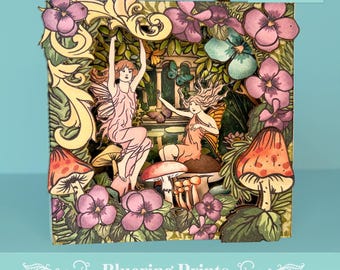 Puede incluir: Una obra de arte en papel en capas que presenta dos hadas en una escena de jardín caprichosa con setas, flores y mariposas. La obra de arte tiene una etiqueta de descarga digital y el texto "Bluering Prints". Se adjunta una cinta dorada para colgar.