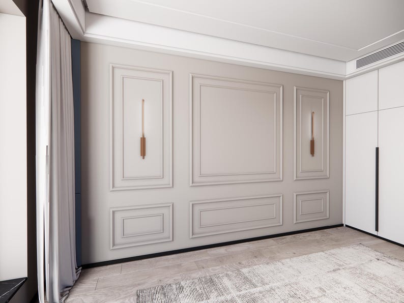 Puede incluir: Una pared blanca con un dise&ntilde;o de molduras decorativas. La pared tiene dos apliques de pared rectangulares con un acabado dorado. La pared est&aacute; en una habitaci&oacute;n con una alfombra blanca en el suelo.