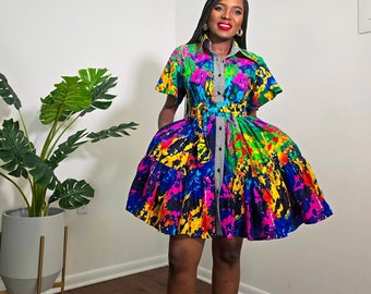 May include: A colorful short-sleeved dress with a button-up front and a tie belt. The dress has a black and white striped pattern on the front and a colorful abstract print on the skirt.