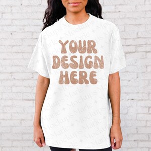 May include: White t-shirt mockup with the text "YOUR DESIGN HERE" in brown letters with a distressed look.