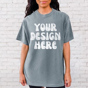 May include: A blue t-shirt with the text "YOUR DESIGN HERE" in white, retro-style lettering.
