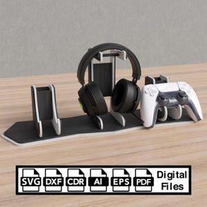 May include: A wooden gaming headset and controller stand in black and white. The stand has spaces for a headset, controller, and other devices. The text "Digital Files" is visible. The stand is designed to hold gaming accessories.