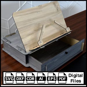Könnte beinhalten: Eine Holzkiste mit einem Scharnierdeckel, der sich öffnet und einen Schubkasten enthüllt. Die Kiste ist aus hellem Holz mit einer grauen Beize. Die Schublade ist aus dunklem Holz mit einer grauen Beize. Die Kiste ist so konzipiert, dass sie Gegenstände wie Bücher, Fotos oder andere kleine Gegenstände aufbewahrt und präsentiert. Die Kiste ist als digitale Datei zum Download verfügbar.