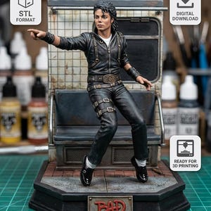 May include: A 3D printed figurine of a person with dark hair wearing a black leather jacket, black pants with buckles, and black shoes. The figure is posed in a dynamic stance on a subway-themed base with a plaque that reads BAD in red letters.