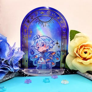 May include: A clear acrylic stand featuring a cartoon character with light blue hair and clothing. The character stands in front of a blue archway with gold accents and a starry sky design. Small star-shaped decorations are scattered in front.