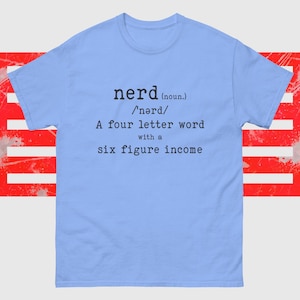 Puede incluir: Camiseta azul claro con una definición humorística de la palabra "nerd" impresa en la parte delantera. La definición dice: "nerd (sustantivo) /'nərd/ Una palabra de cuatro letras con un ingreso de seis cifras."
