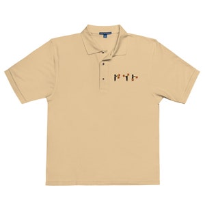 May include: A beige polo shirt with a small embroidered design of stick figures holding flags. The flags are red, yellow, and black.