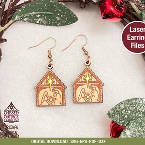 Könnte beinhalten: Lasergeschnittene Holzohrringe mit einer Krippenszene in einem hausförmigen Design. Die Ohrringe haben eine hellbraune Farbe mit goldfarbenen Akzenten und einem Stern. Der Text "Laser Earring Files" ist sichtbar. Die Ohrringe hängen an goldfarbenen Haken.