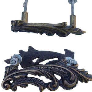 May include: Two ornate, antique-style cabinet pulls with a scrolled, leaf-like design. The pulls are made of metal with a dark bronze finish and have a screw-on mounting.