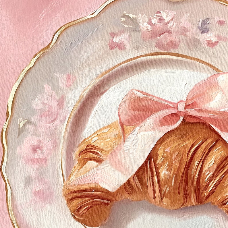 May include: A still-life painting of a croissant tied with a pink bow, resting on a white plate with a gold rim and floral accents. The background is a soft pink, creating a delicate and inviting aesthetic.