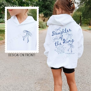 May include: White hoodie with the text "Daughter of the King" in blue script on the back, along with a bow graphic. The front of the hoodie features a bow graphic and the name "Emma".