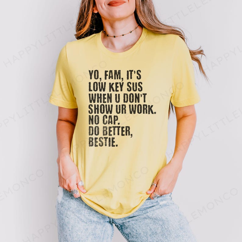 May include: A light yellow t-shirt with black text that reads "YO, FAM, IT'S LOW KEY SUS WHEN U DON'T SHOW UR WORK. NO CAP. DO BETTER, BESTIE." The shirt is a casual style.