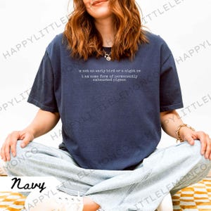 Puede incluir: Camiseta azul marino con el texto blanco: "I'm not an early bird or a night owl, I am some form of permanently exhausted pigeon". La camiseta tiene un corte holgado y mangas cortas.