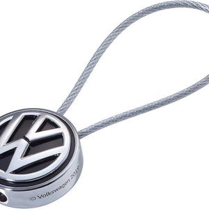 May include: A silver key chain with a black and silver Volkswagen logo. The logo is surrounded by a silver ring and the text "Volkswagen 2018" is printed on the bottom.