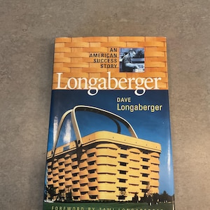 May include: A book titled "Longaberger: An American Success Story" features a woven basket design on the cover. The cover also includes the author's name, Dave Longaberger, and the words "Foreword by Tami Longaberger."