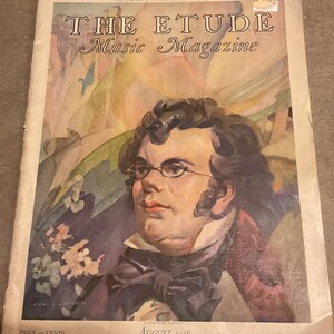 May include: The August 1928 issue of The Etude Music Magazine, featuring a watercolor-style portrait of a man with dark curly hair and glasses. The cover includes the text The Journal of the Musical Home Everywhere and A Schubert Fantasy.