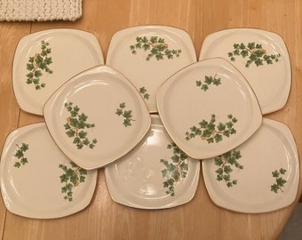 May include: Set of eight white square ceramic plates with a gold trim and a green ivy design.