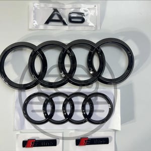 May include: Black Audi car emblems and badges. Includes the four-ring logo, "A6" lettering, and "S Line" badges with red accents. All items are new and packaged.