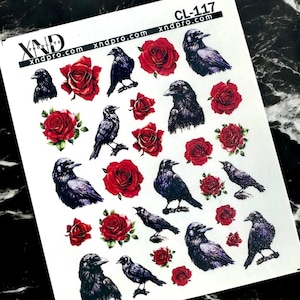 Puede incluir: Hoja de pegatinas para decoración de uñas con cuervos negros y rosas rojas. Los cuervos se muestran en varias poses, y las rosas están en plena floración. La hoja incluye el texto "xndpro.com" y "CL-117".
