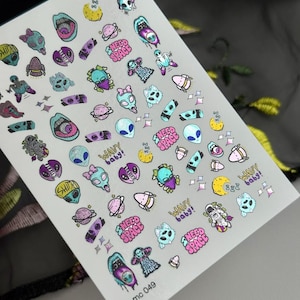 May include: Sheet of nail art stickers featuring colorful alien designs, planets, and text like "Wavy baby!" and "Need Space." The stickers include various alien characters in shades of blue, purple, and pink. The sheet is labeled "mc 049."