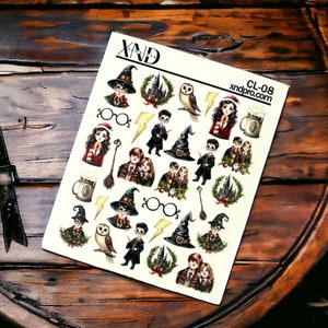 Op de afbeelding: Een vel stickers met verschillende illustraties met Harry Potter-thema, waaronder personages, voorwerpen en symbolen. De stickers zijn gedrukt op wit papier en hebben een glanzende afwerking. Het vel is gelabeld met "CL-08" en "xndpro.com".