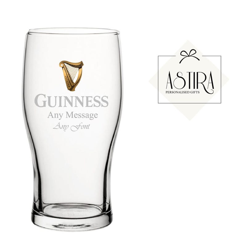 May include: A clear pint glass with the Guinness logo and text. The logo features a gold harp. The text on the glass reads "GUINNESS" above "Any Message" and "Any Font". A logo for "ASTIRA PERSONALIZED GIFTS" is to the right.