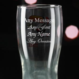 May include: A clear glass with the words "Any Message, Any Font, Any Name, Any Occasion" in white script. A toucan illustration is visible. The glass is designed for personalization and is suitable for various events.