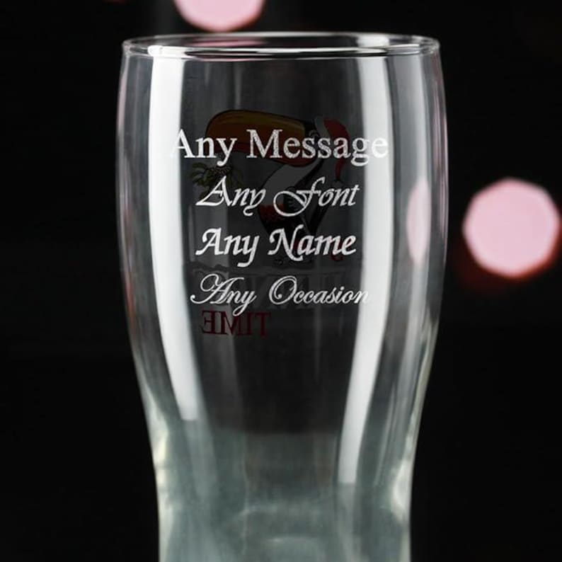 May include: A clear glass with the words "Any Message, Any Font, Any Name, Any Occasion" in white script. A toucan illustration is visible. The glass is designed for personalization and is suitable for various events.