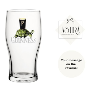 May include: A clear pint glass with a Guinness logo featuring a turtle carrying a pint of stout. The glass has a curved shape and a wide mouth. The text "Guinness" is printed below the turtle.