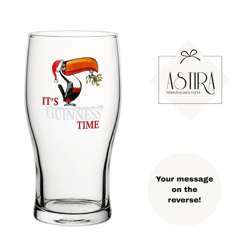 May include: A clear pint glass with a cartoon toucan wearing a Santa hat and holding mistletoe. The text "IT'S GUINNESS TIME" is printed on the glass. The glass is a promotional item for Guinness.