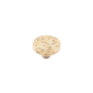 May include: A round, cream-coloured cabinet knob with a speckled pattern. The knob has a silver base.
