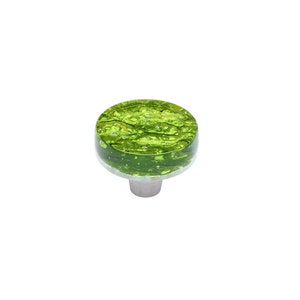 Peut inclure: Un bouton de porte rond en verre vert avec une base argentée. Le verre a un aspect texturé et marbré avec de petites bulles d'air.