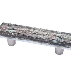 May include: A rectangular glass cabinet pull with a silver finish and a mottled, multi-coloured pattern. The pull has two silver mounting screws.