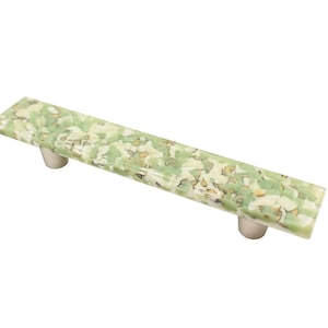 May include: A green and white patterned cabinet pull with a rectangular shape and two silver knobs.