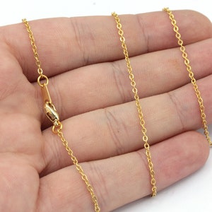 May include: A delicate gold-colored chain necklace with a lobster clasp. The chain is composed of small, evenly spaced oval links. The necklace is displayed against a neutral background.