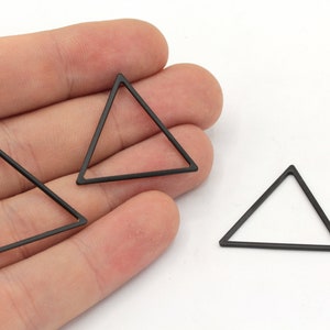May include: Three black metal triangle shapes. The triangles are hollow and have a simple, geometric design.