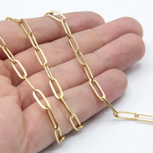 Könnte beinhalten: Eine goldfarbene Kette mit ovalen Gliedern. Die Kette liegt auf einer Hand.