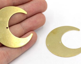 May include: Two gold-toned metal crescent moon charms with three holes each. The charms are approximately 2 inches in diameter.